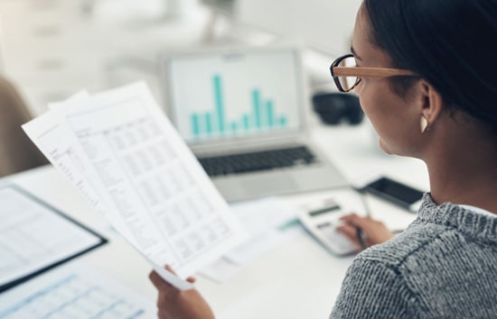 Woman working at desk looking at financial documents Woman working at desk looking at financial documents