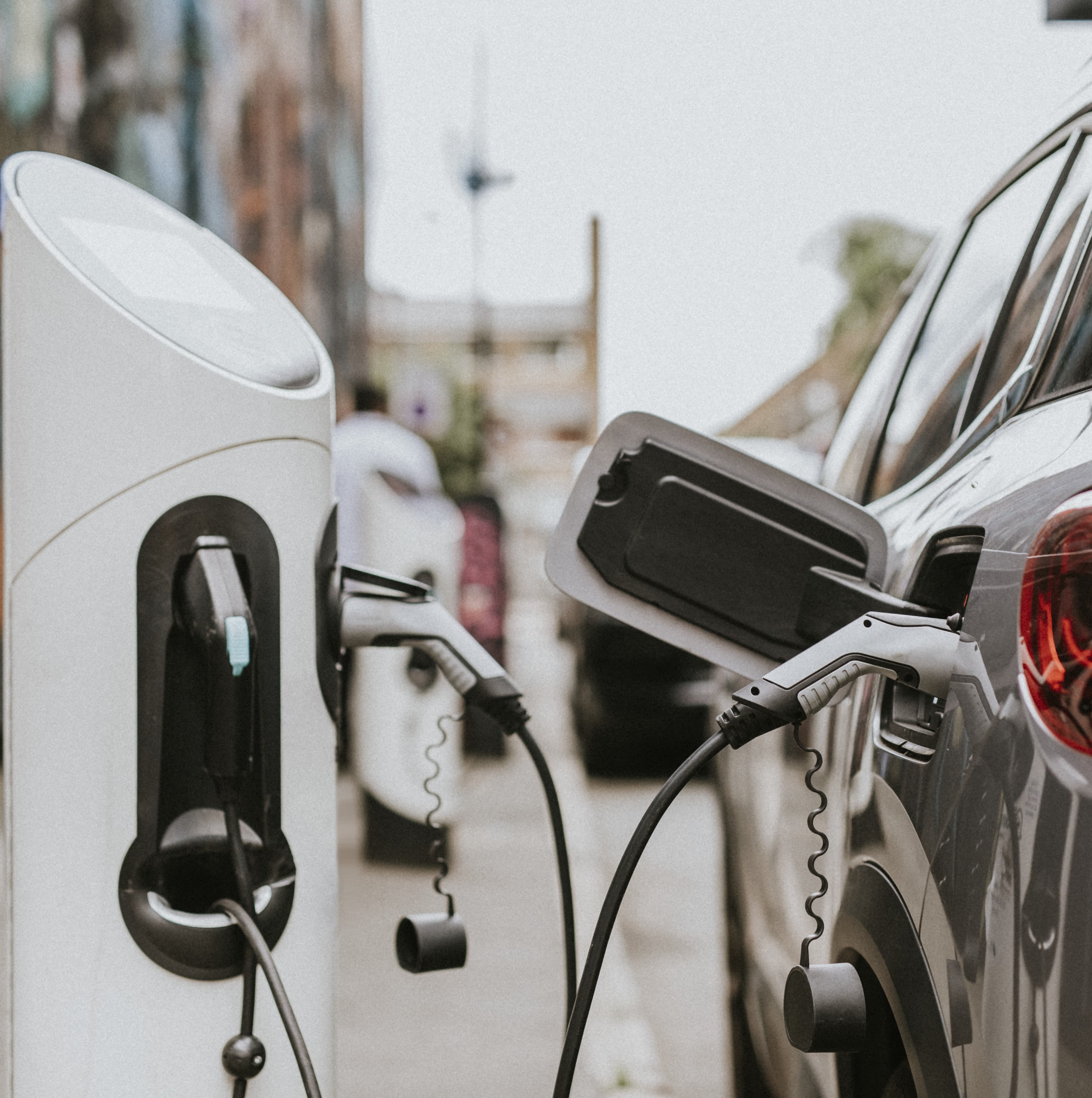 Electric fleet vehicles plugged into charging stations along a city street, highlighting EV charging infrastructure. Electric fleet vehicles plugged into charging stations along a city street, highlighting EV charging infrastructure.